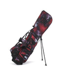 A red golf stand bag with a geometric galaxy pattern and black studs, displayed on a stand.
